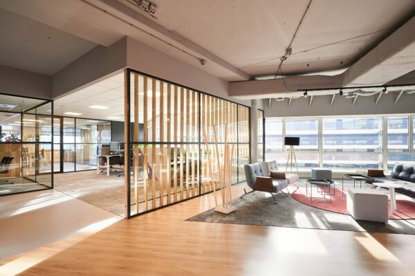 Moderne kantoorruimte aan de Statenlaan 1-27 met glazen wanden, houten details en een loungehoek met zithoeken en veel daglicht.