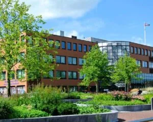 Kantoorgebouw aan het Stationsplein met een tuin vol groen en bloemen op de voorgrond.