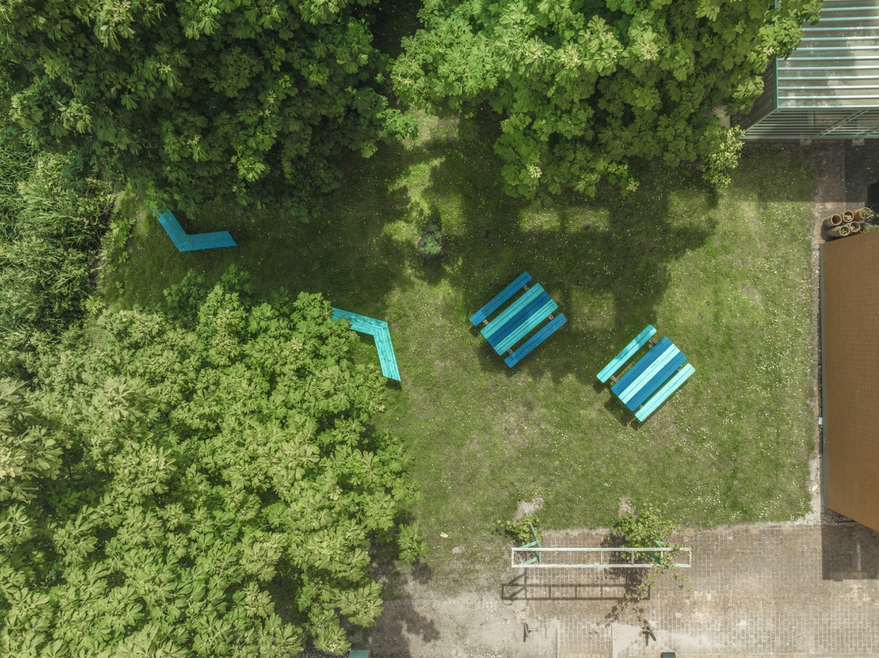Luchtfoto van Terras 4 groot met blauwe picknicktafels en bankjes tussen groene bomen.