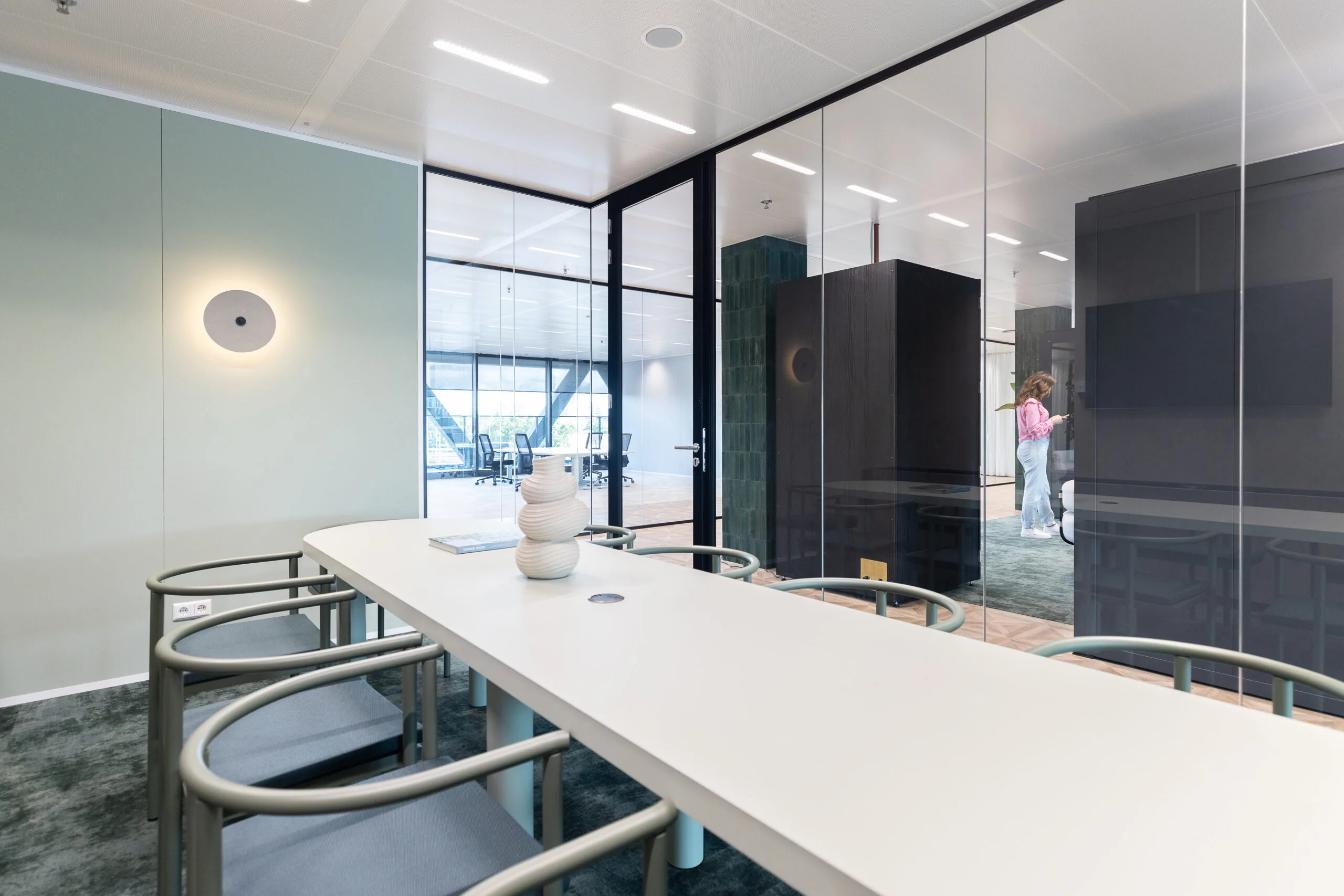 Moderne vergaderruimte in The Joan-12 met minimalistisch interieur, glazen wanden en designmeubilair.