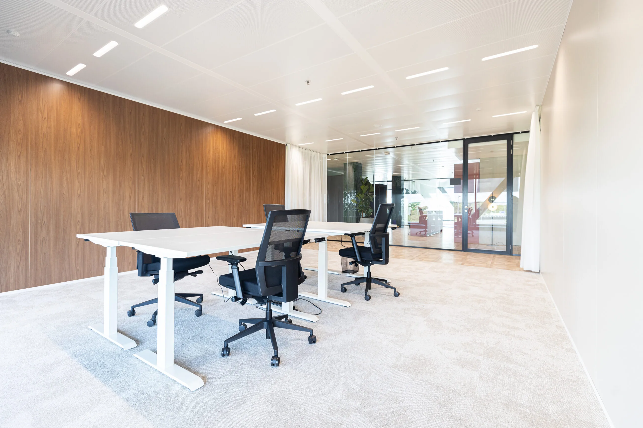Moderne kantoorruimte in The Joan-25 met verstelbare bureaus, ergonomische stoelen en glazen wanden.