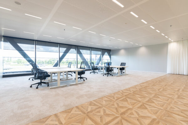 Moderne, ruime kantoorruimte in The Joan-29 met grote ramen, bureaus en ergonomische stoelen.