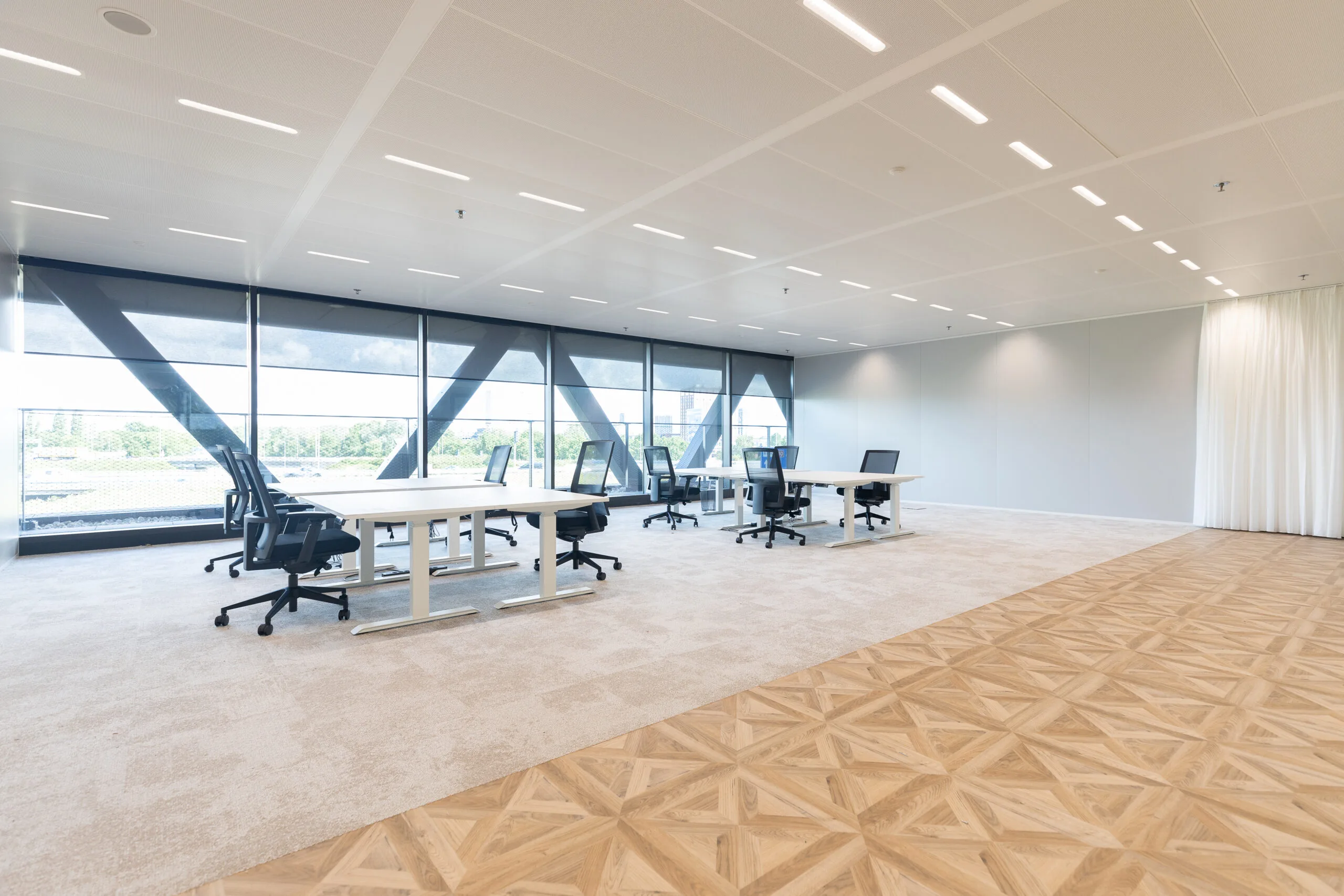 Moderne, ruime kantoorruimte in The Joan-29 met grote ramen, bureaus en ergonomische stoelen.