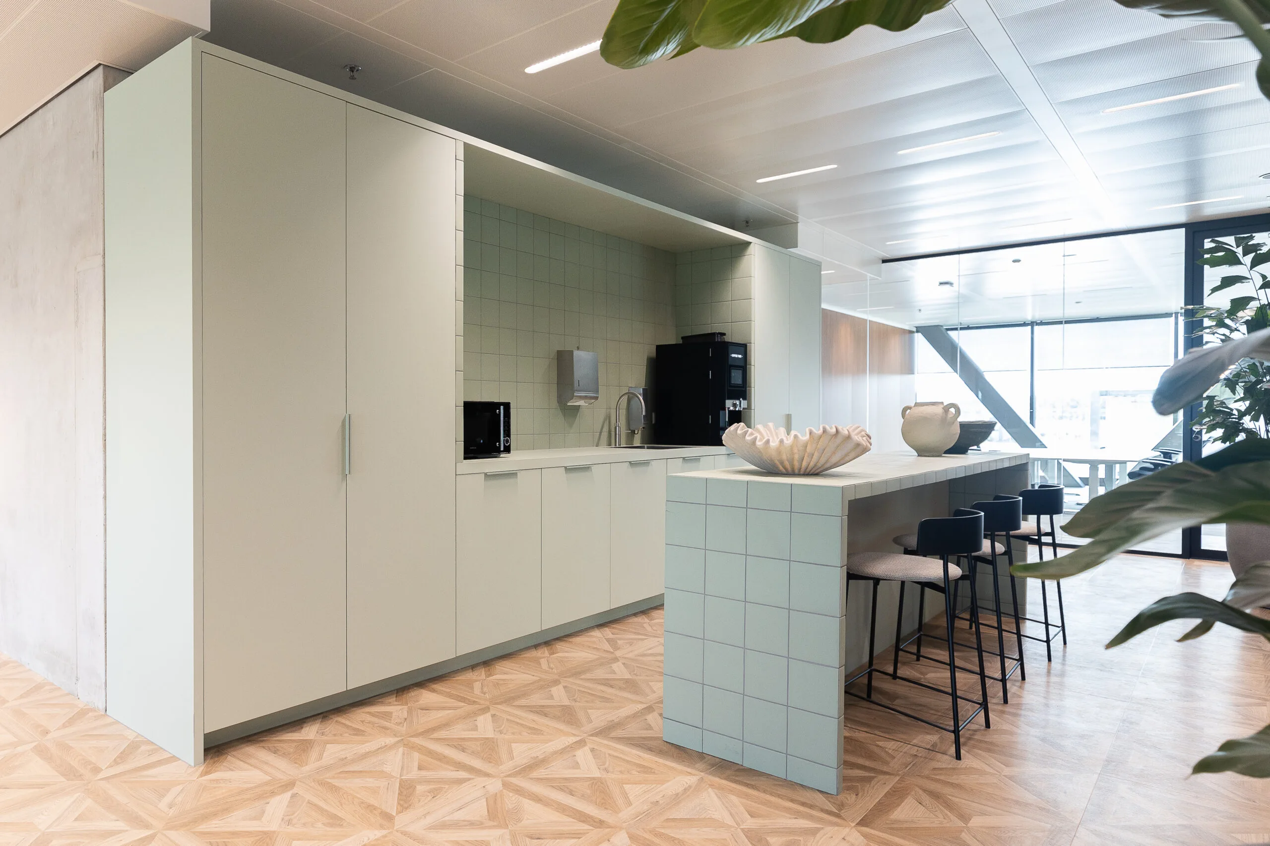 Moderne kantoor-keuken in The Joan-5 met mintgroene kasten, betegelde bar en decoratieve aardewerken objecten.