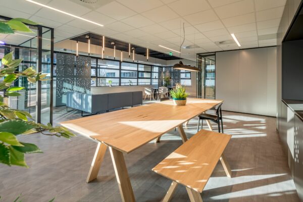 Moderne en licht ingerichte kantoorruimte aan de Tielweg 30 met houten vergadertafel, zitbanken en glazen wanden.
