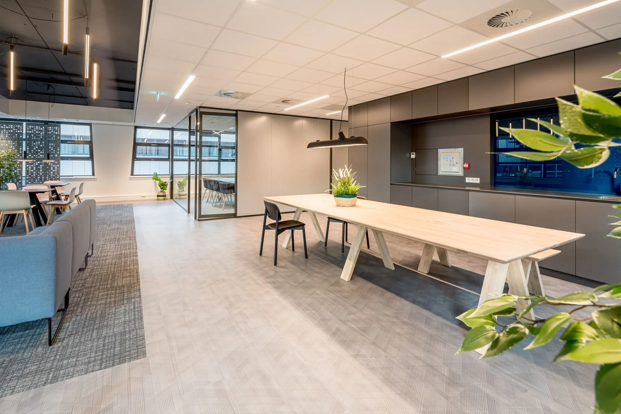 Moderne, open kantoorruimte aan de Tielweg 30 met strakke inrichting, houten vergadertafel en glazen vergaderruimte.