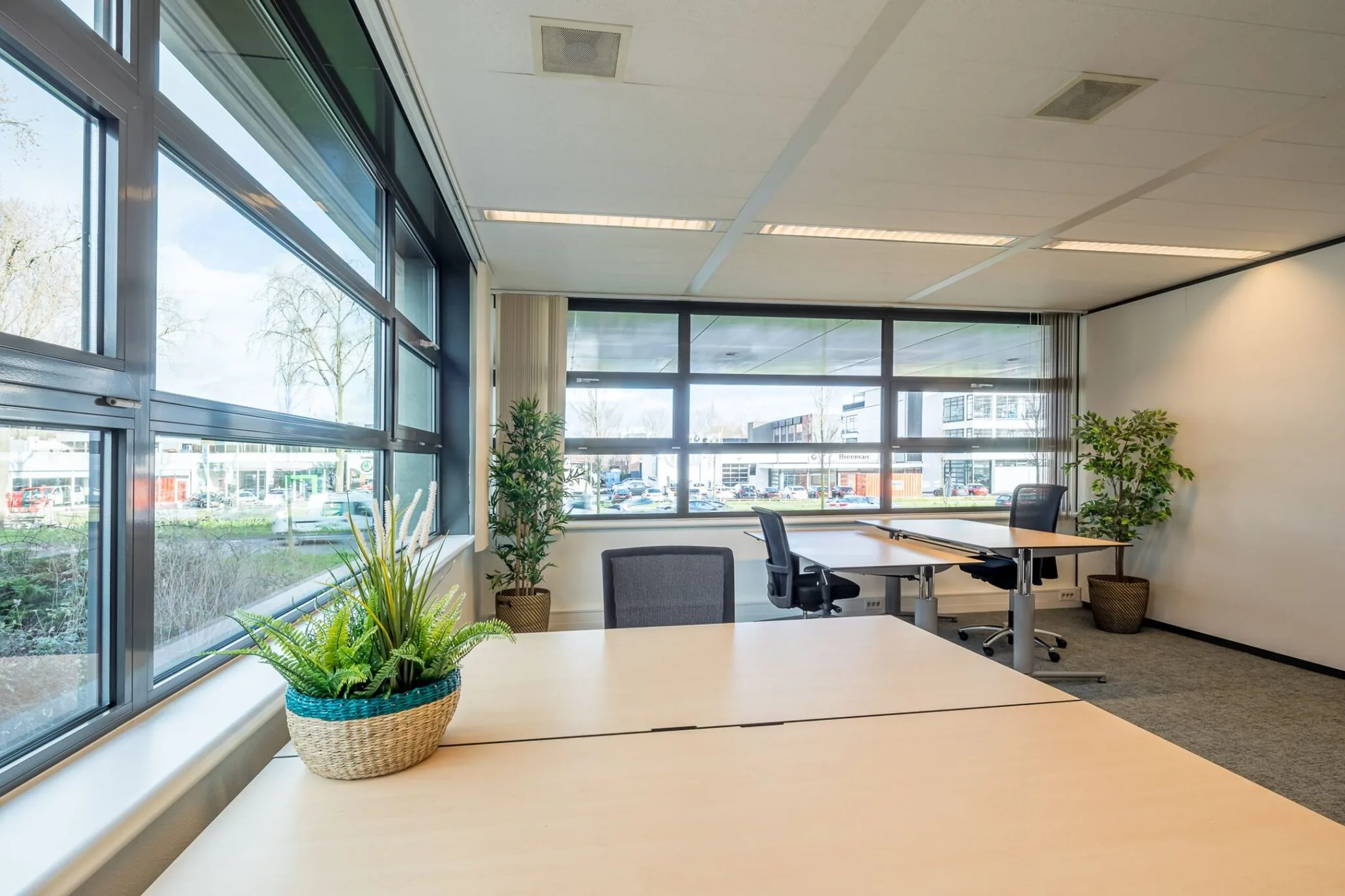 Modern kantoor met grote ramen, meerdere bureaus en planten aan de Tielweg 30.