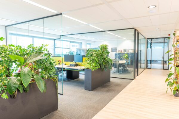 Modern kantoorinterieur aan de Tupolevlaan 41 met glazen vergaderruimtes, bureaus en veel groen.