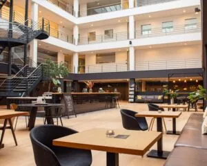 Moderne, open binnenruimte van een kantoor in Utrecht met zitjes, een koffiebar en meerdere verdiepingen met kantoren.