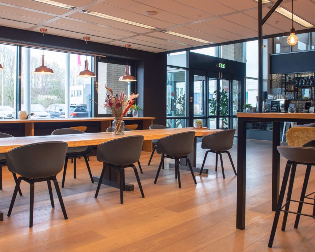 Moderne en sfeervolle kantine in Utrecht met lange houten tafels, zwarte stoelen en grote ramen.