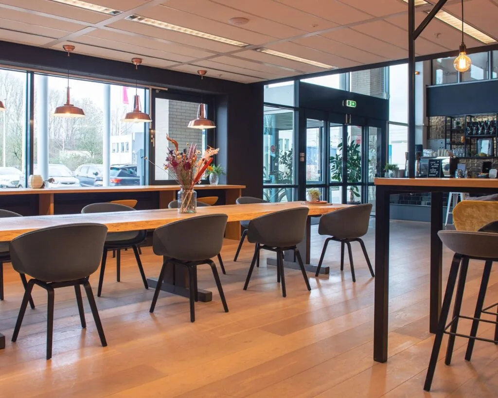 Moderne en sfeervolle kantine in Utrecht met lange houten tafels, zwarte stoelen en grote ramen.