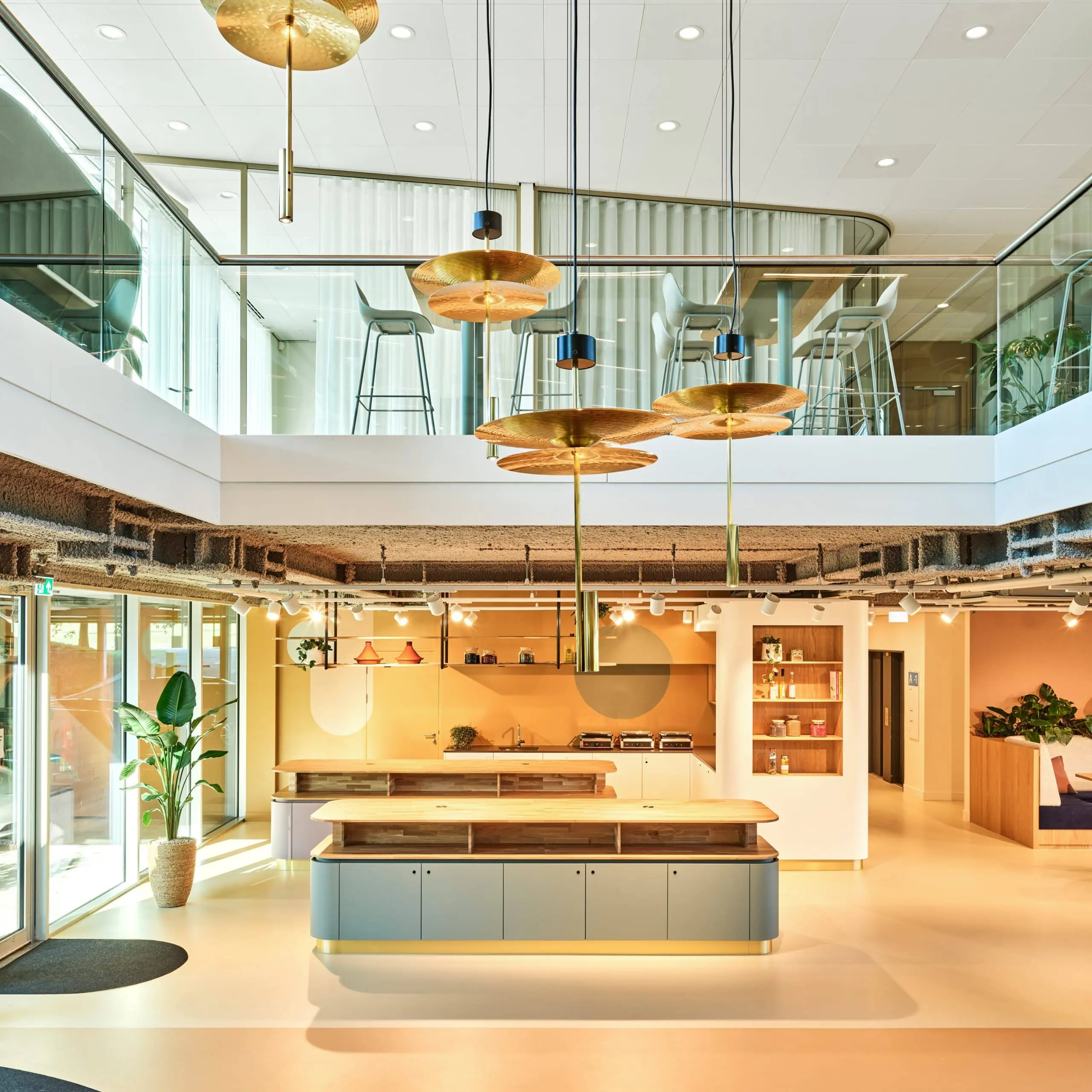 Moderne, open kantoorruimte aan de Van Deventerlaan 30-40 met een keuken, zitgedeelte en bovenverdieping met glazen balustrade.