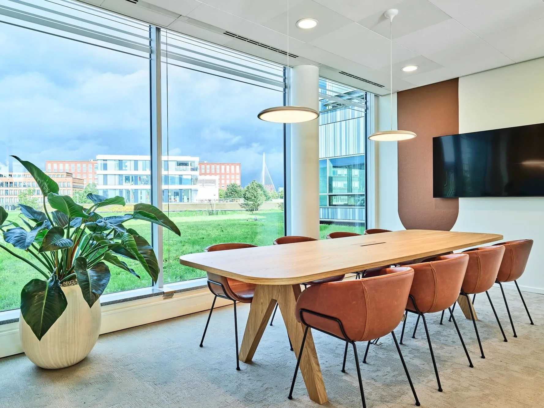 Moderne vergaderruimte aan de Van Deventerlaan 30-40 met houten tafel, leren stoelen, grote raampartijen en uitzicht op buiten.