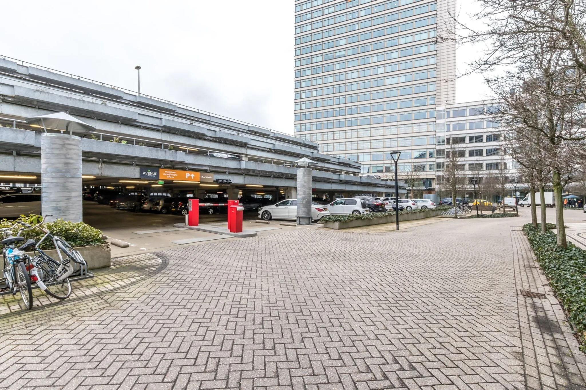 Parkeergarage bij Vliegend Hertlaan 21 met meerdere verdiepingen, omringd door kantoren en een geplaveide wandelroute.