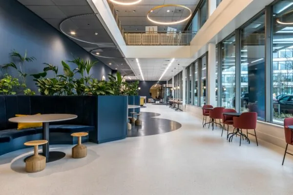 Moderne en licht ingerichte kantoorlobby aan de Vliegend Hertlaan 21 met zitgedeeltes, planten en grote ramen.