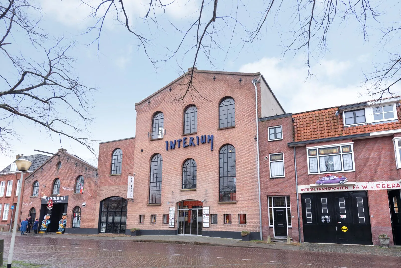 Voorgevel van het Suikercomplex met bakstenen panden, grote raampartijen en de ingang van het INTERIUM-gebouw.