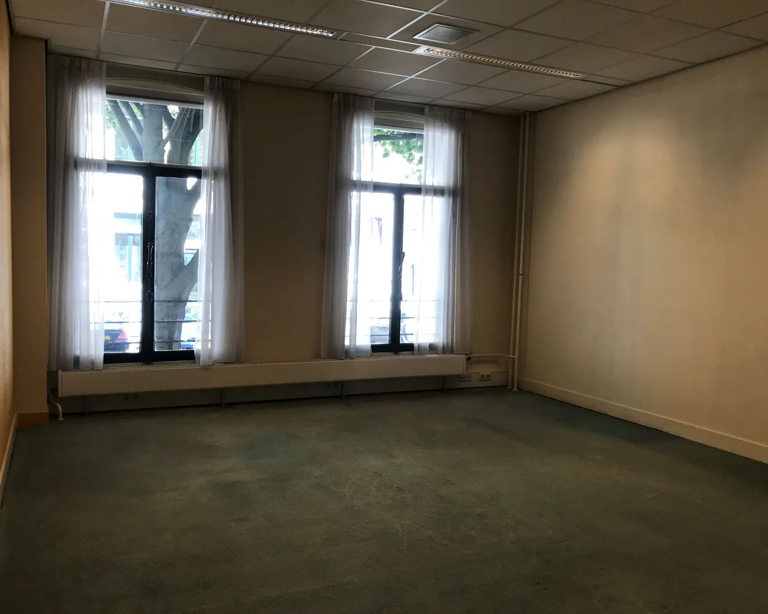 Lege kantoorruimte met twee grote ramen aan de voorzijde van het pand aan de Burgemeester van Karnebeeklaan in Den Haag.