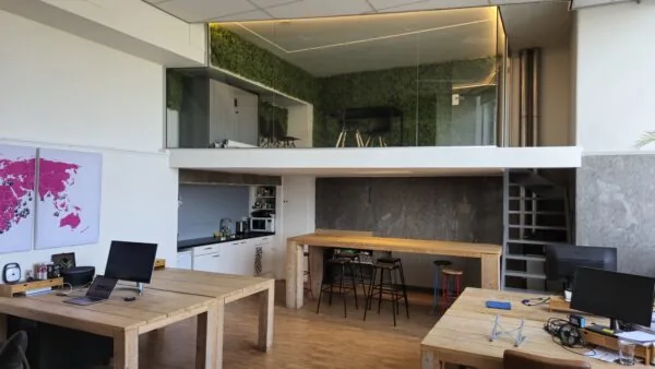 Moderne kantoorruimte op WG-plein 100 unit 478 met houten bureaus, een keuken, een trap en een glazen vergaderruimte op de vide.