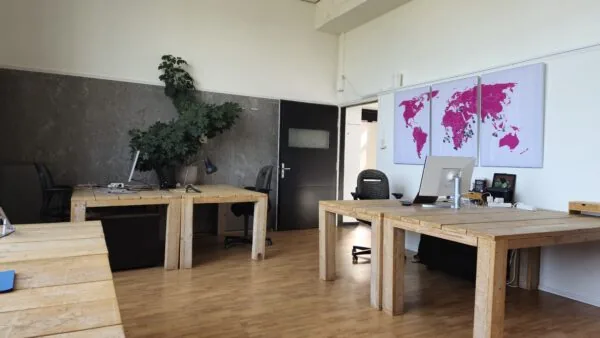 Kantoorruimte in WG-plein 100 unit 478 met houten bureaus, bureaustoelen, computers en een wereldkaart aan de muur.