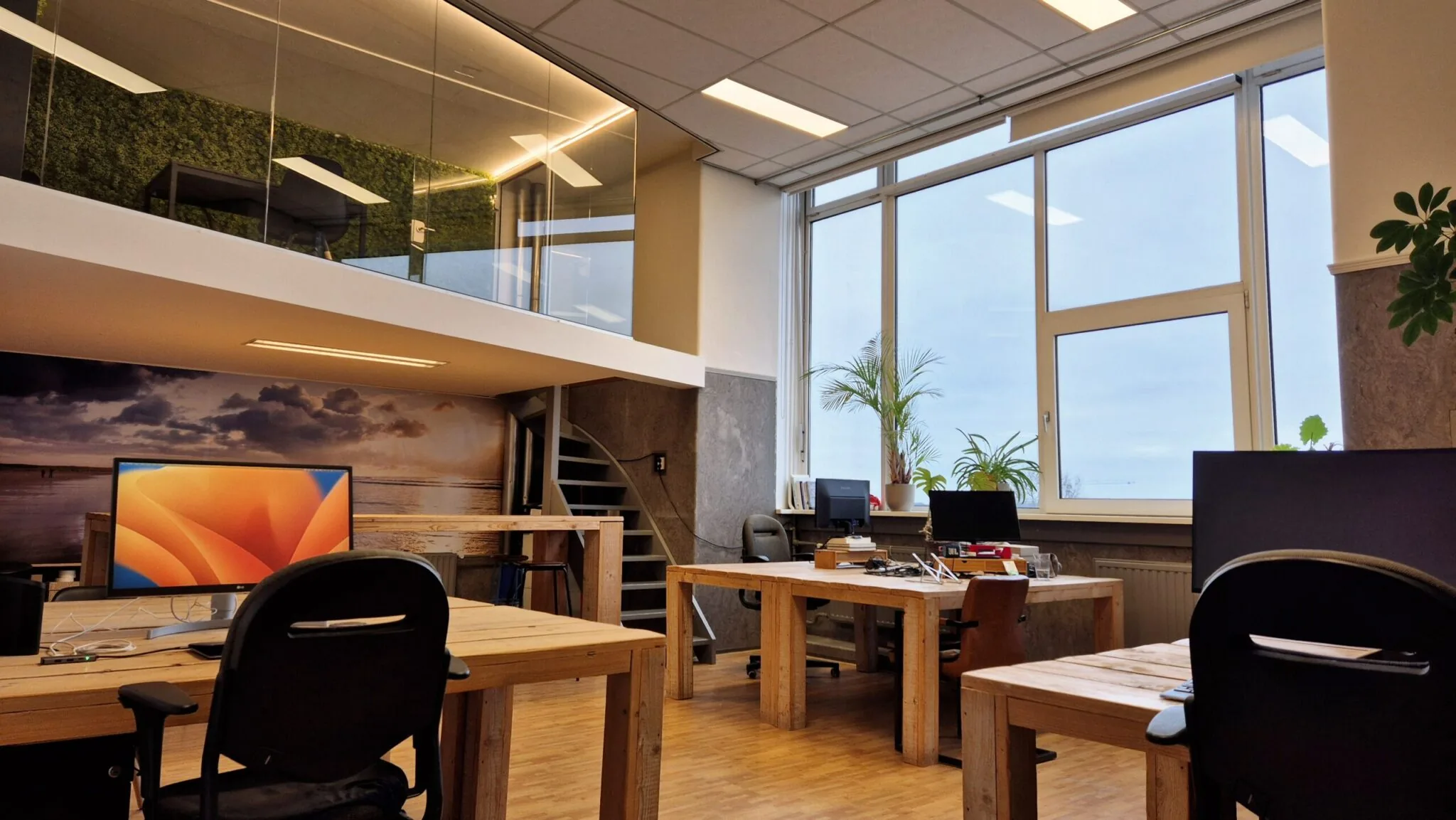 Modern kantoorinterieur in WG-plein 100, unit 478, met houten bureaus, grote ramen en een vide met groene wand.