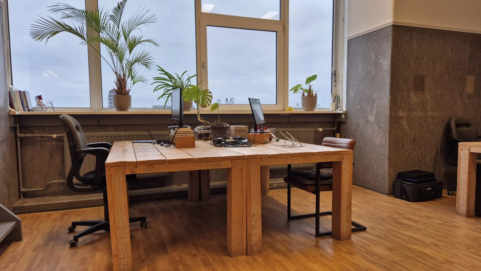 Twee houten bureaus met computeropstellingen en kamerplanten in een kantoorruimte op WG-plein 100, unit 478.