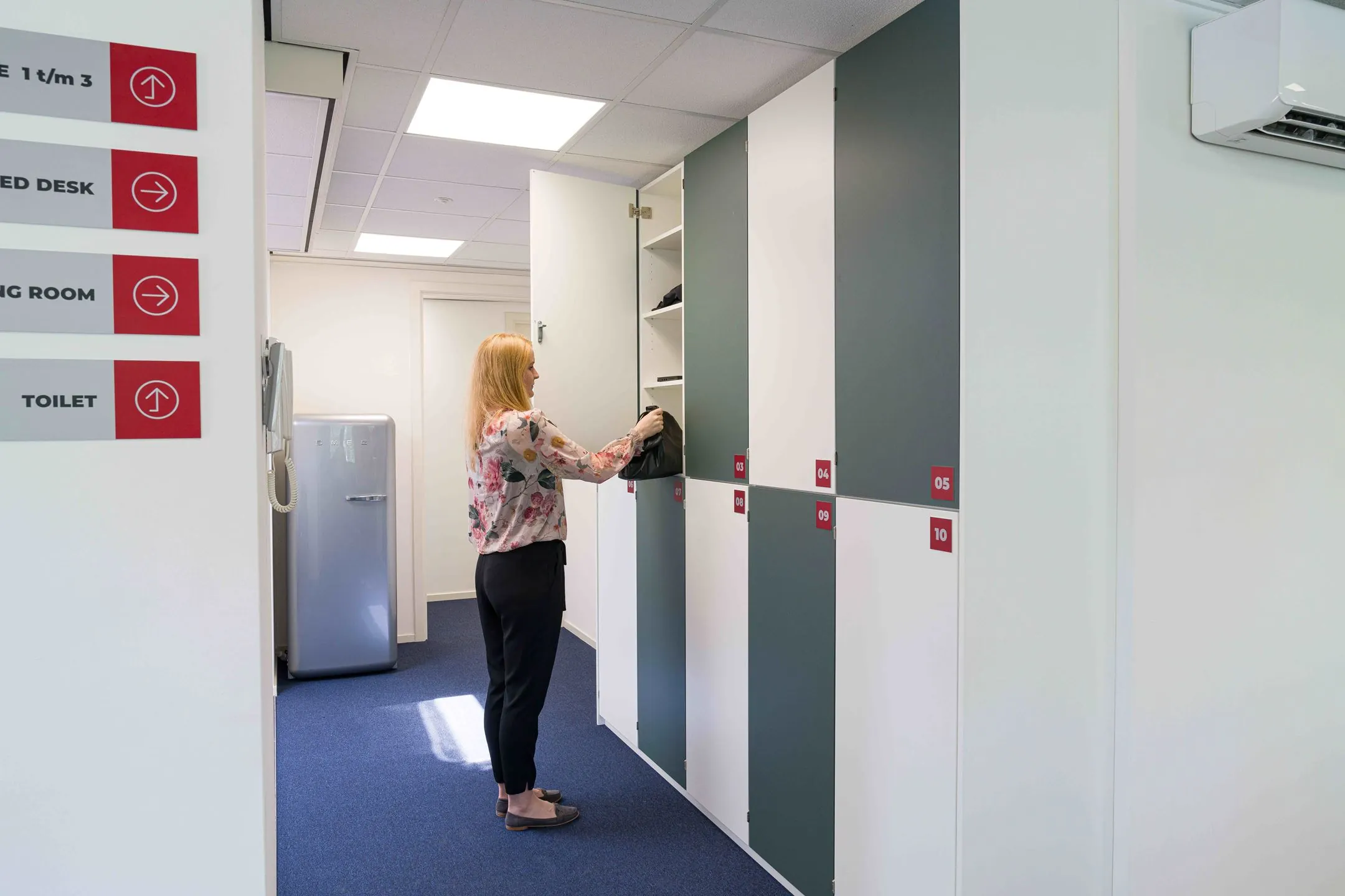 Vrouw bergt tas op in een locker in een modern kantoor aan de Waarderweg 33.