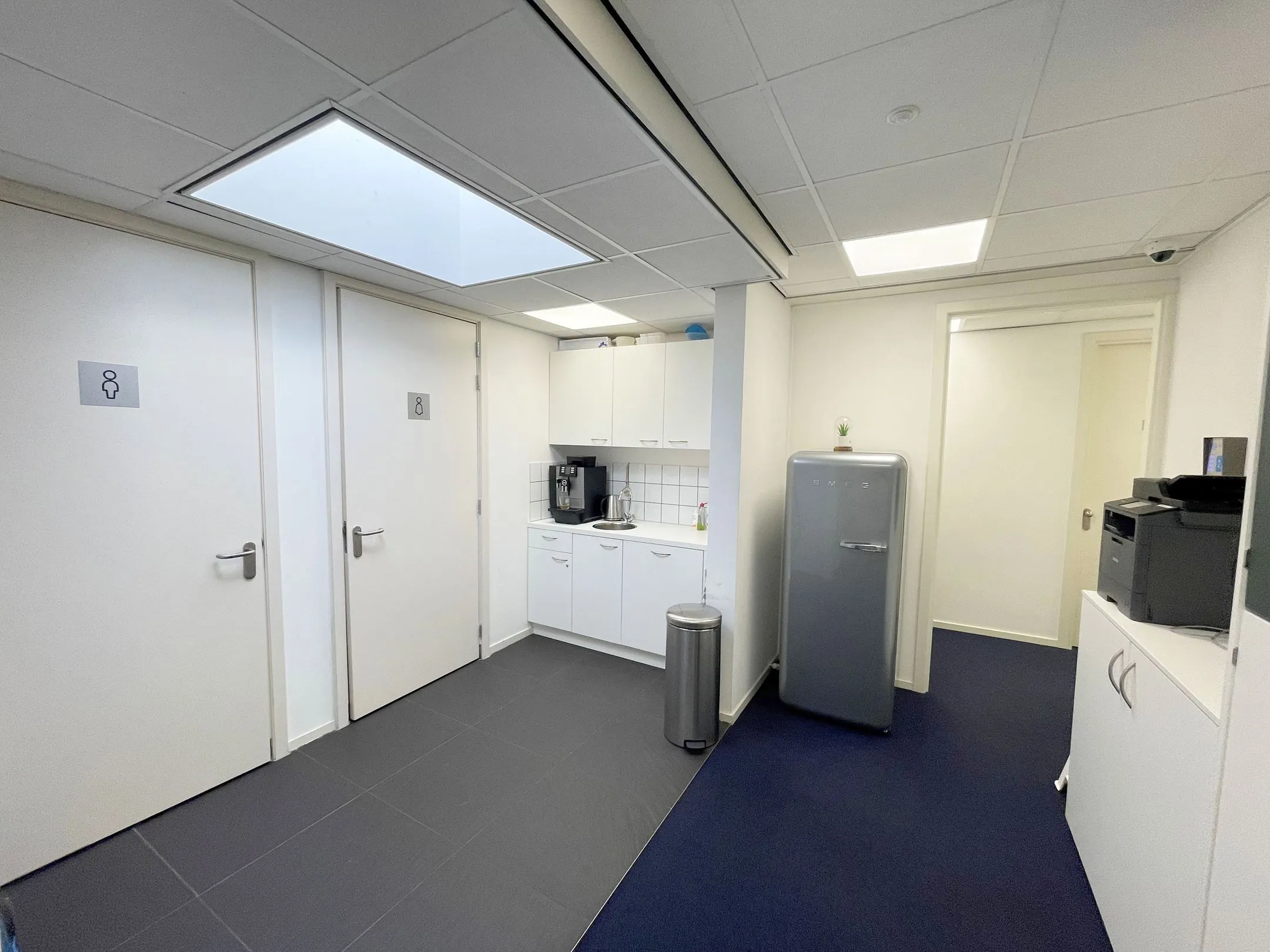 Kleine kantoorpantry aan de Waarderweg 33 met koelkast, koffiezetapparaat, printer en toiletruimtes.