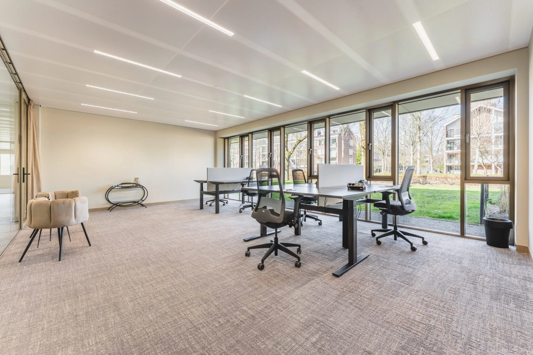 Modern kantoorinterieur Walborg_2_11 met bureaus, ergonomische stoelen en grote ramen met uitzicht op een groene buitenruimte.