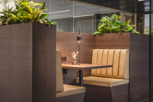 Moderne zitplek in Walborg 2.30 met lederen banken, houten tafel, sfeerverlichting en omringende planten.