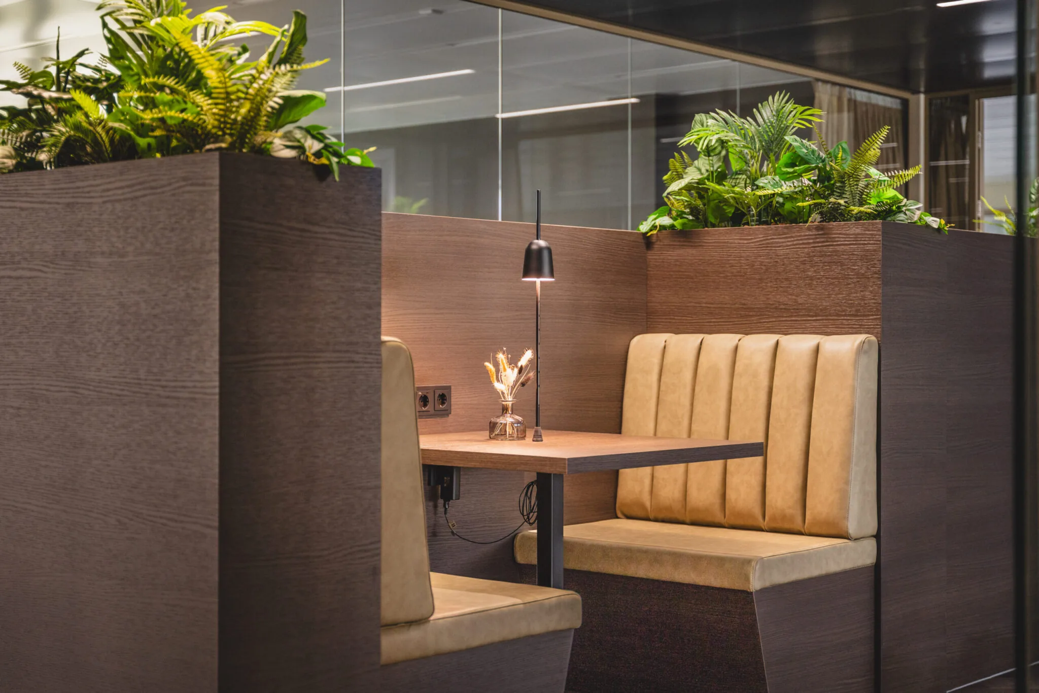 Moderne zitplek in Walborg 2.30 met lederen banken, houten tafel, sfeerverlichting en omringende planten.