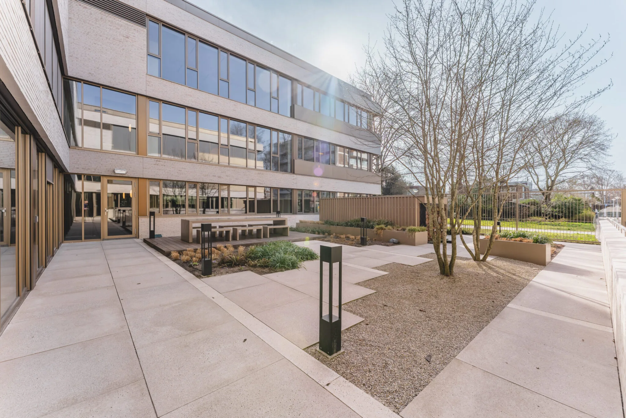 Binnenplaats van het Walborg-gebouw met moderne bestrating, zitbanken en aangelegde beplanting bij een kantoorpand.
