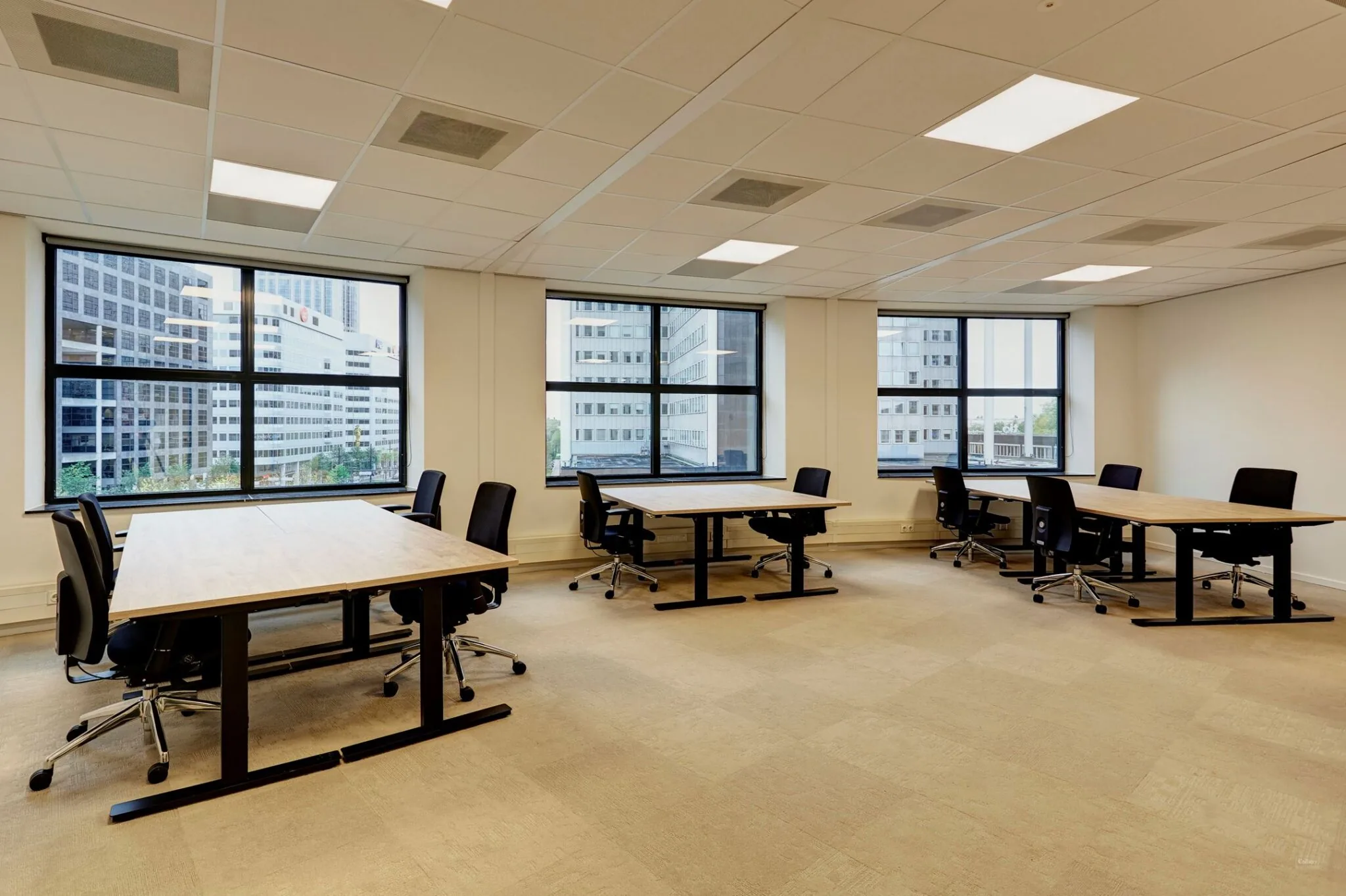 Ruime en moderne kantoorruimte aan Weena 335 met meerdere bureaus en grote ramen met uitzicht op omliggende kantoorpanden.