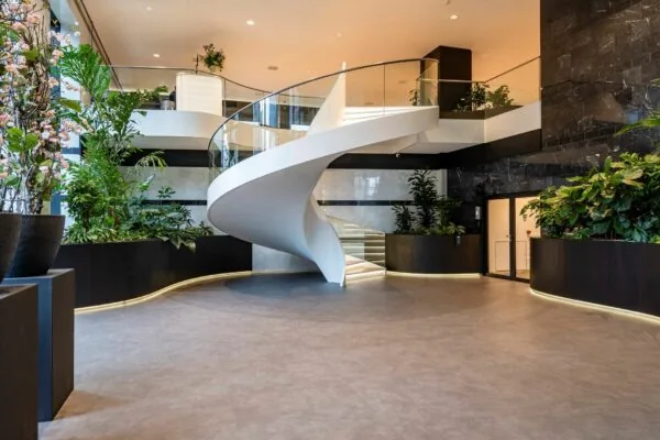 Moderne entreehal van Weena 335 met een witte, spiraalvormige trap en veel groenvoorziening.