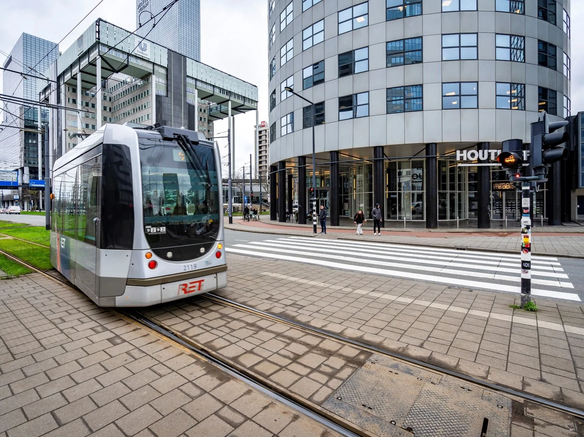 Moderne RET-tram rijdt langs het kantoorgebouw Weena 335 in Rotterdam bij een zebrapad.