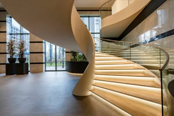 Lichtgevende, moderne spiraaltrap in de entreehal van Weena 335 met zicht op de stad buiten.