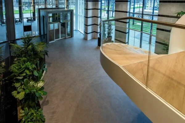 Moderne entreehal van Weena 335 met glazen draaideur, houten trap en groene planten.