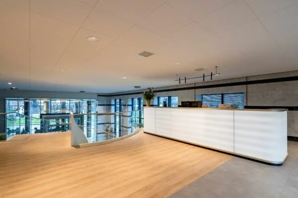 Moderne receptiebalie met houten vloer en glazen balustrade in het kantoorgebouw Weena 335.