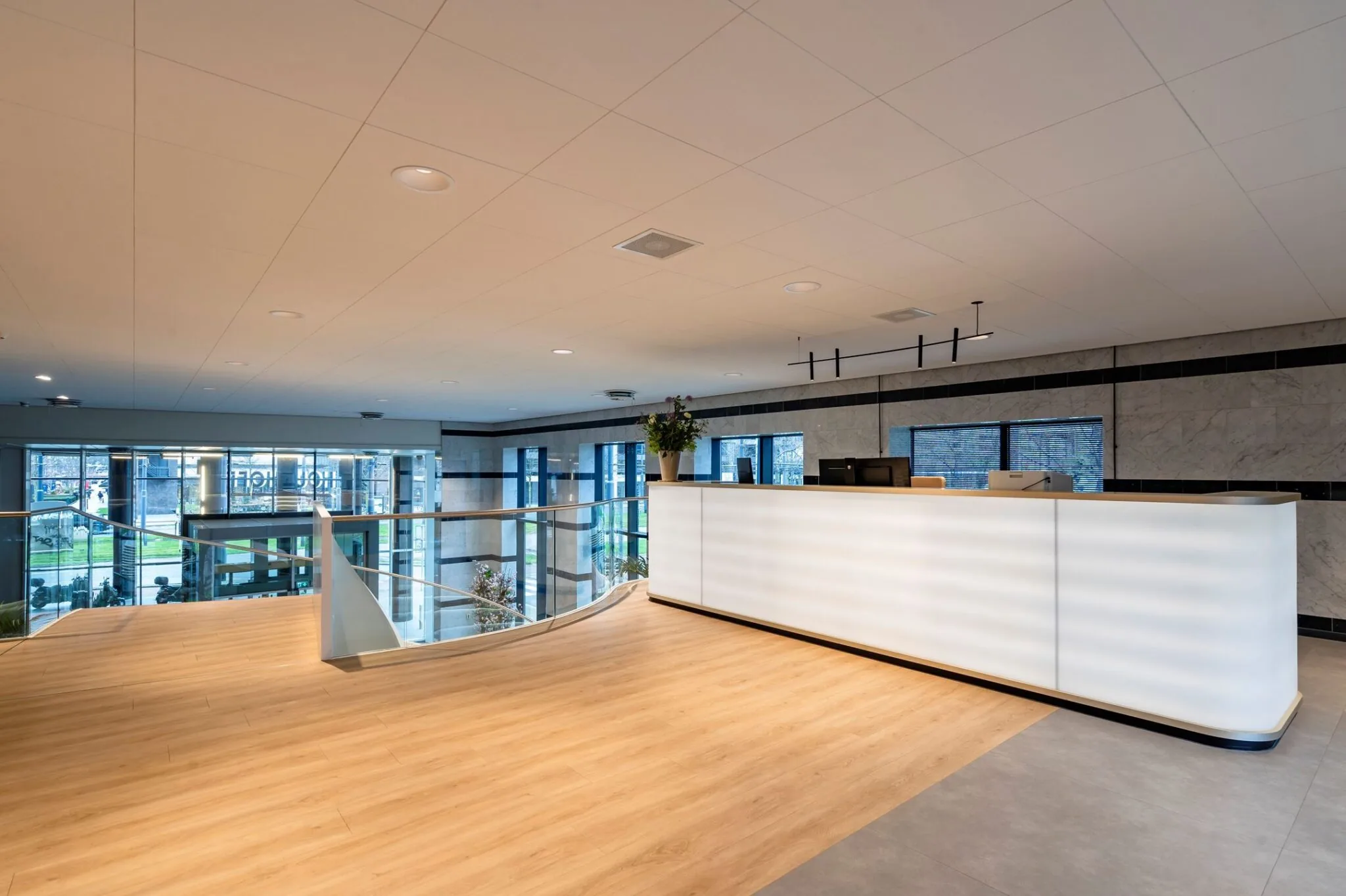 Moderne receptiebalie met houten vloer en glazen balustrade in het kantoorgebouw Weena 335.