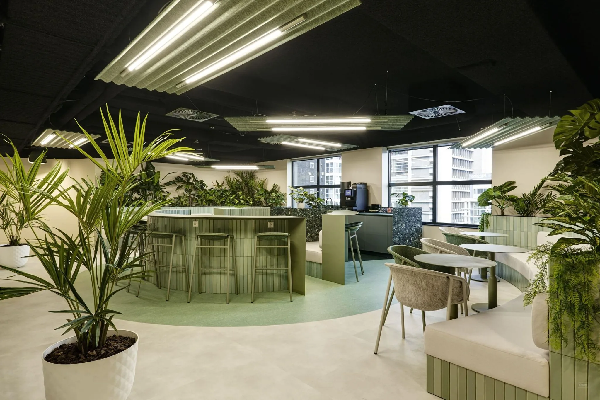 Moderne, groene kantoorlounge in Weena 335 met planten, zitgelegenheden en een koffiecorner.