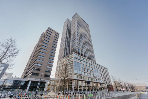 Twee moderne kantoorgebouwen aan de Weena in Rotterdam, met op de voorgrond een rij geparkeerde fietsen en scooters.