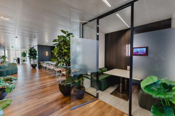 Een moderne kantoorruimte met houten vloeren, groene planten en glazen wanden.