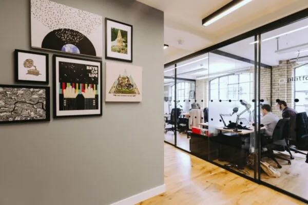 Moderne kantoorruimte aan de Weesperstraat met glazen wanden en kunstwerken aan een grijze muur.