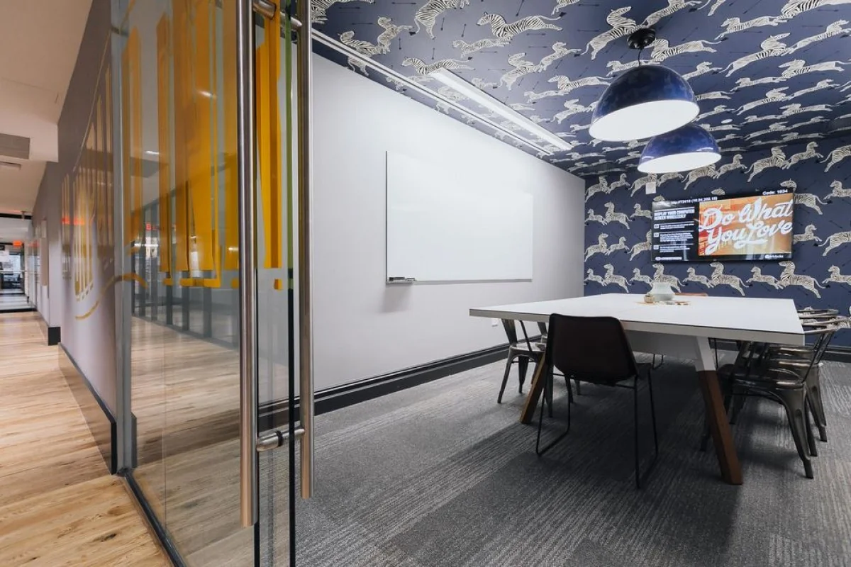 Vergaderruimte in Weesperstaat 61-105 met een grote tafel, kleurrijk zebra-behang en een scherm met de tekst "Do what you love".