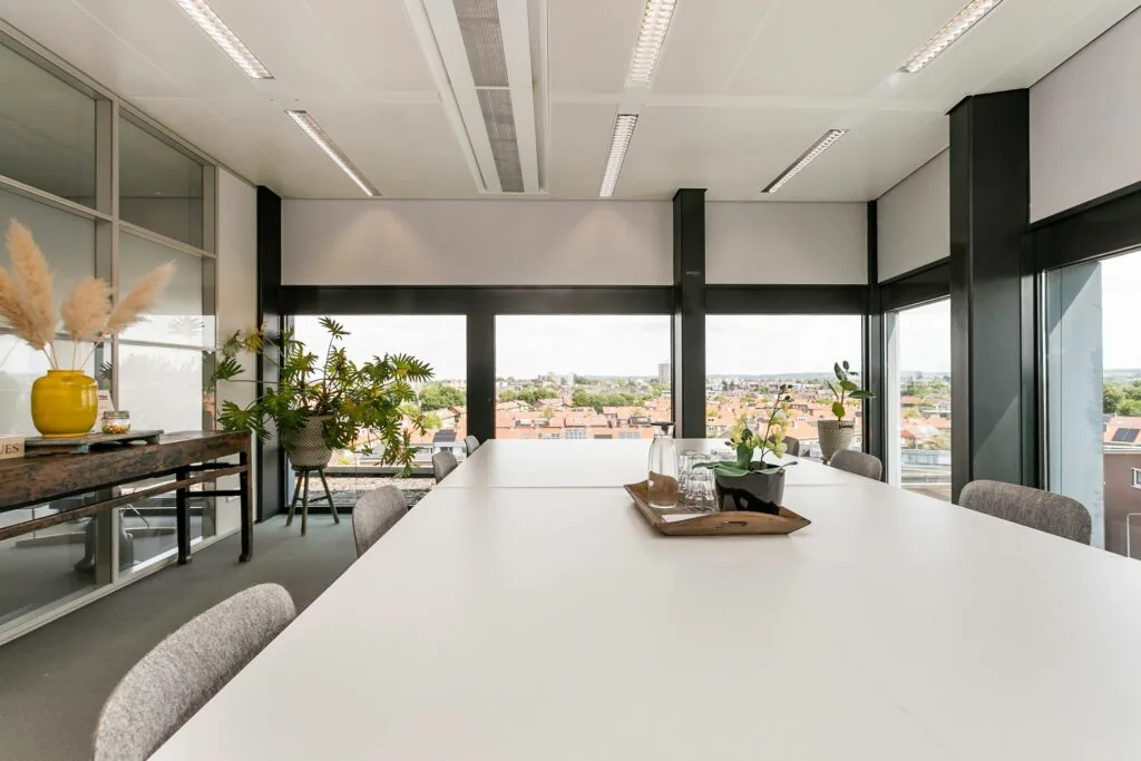 Vergaderruimte met grote ramen, moderne inrichting en uitzicht op de stad vanaf het Wim Duisenbergplantsoen.