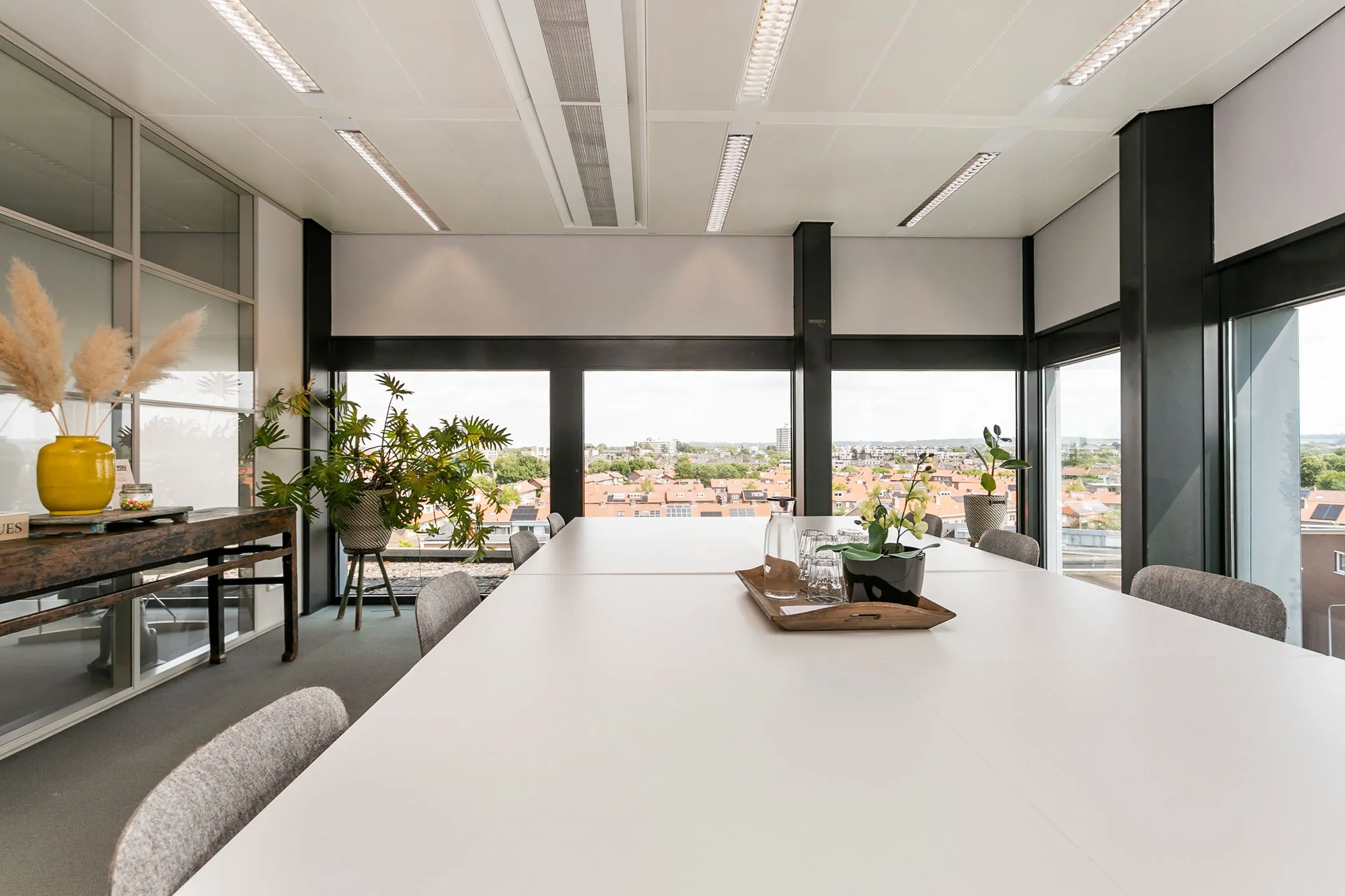 Vergaderruimte met grote ramen, moderne inrichting en uitzicht op de stad vanaf het Wim Duisenbergplantsoen.