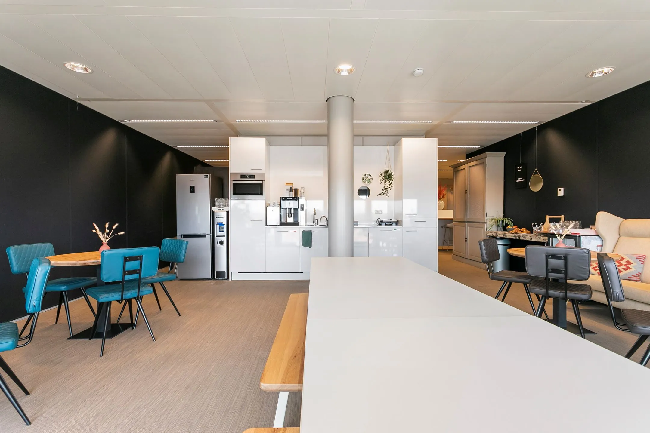 Moderne kantoorkeuken met zithoeken, een lange tafel en witte kastenwand op Wim Duisenbergplantsoen 31.