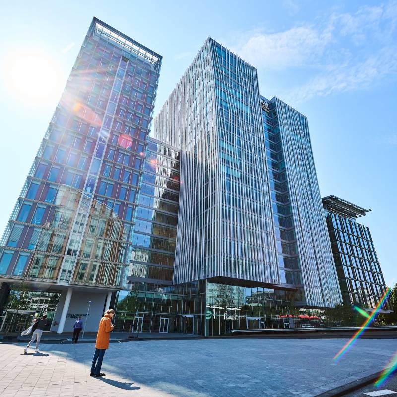 Moderne glasgebouwen met een zonnige hemel en lens flare op de voorgrond.