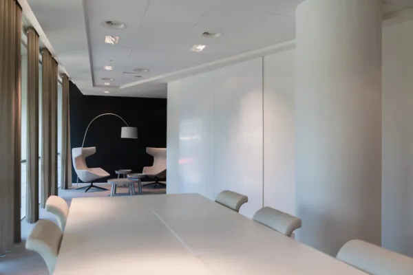 Moderne vergaderruimte in de Zuidtoren met een lange tafel, beige stoelen en een zithoek met designfauteuils en booglamp.
