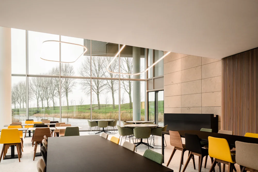 Moderne en lichte zitruimte in de Zuidtoren hall met grote ramen en uitzicht op bomen en water.