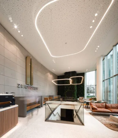 Moderne en stijlvolle lobby van de Zuidtoren met zitgedeelte, natuurwand en opvallende plafondverlichting.